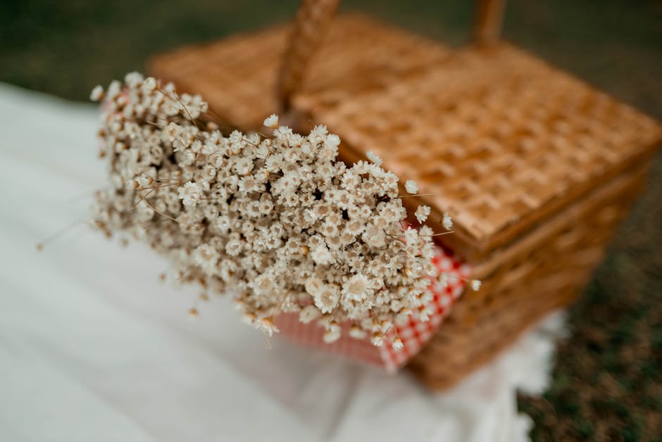 A bouquet of dried white and cream-colored flowers, likely including preserved waxflowers with tiny round petals, is arranged loosely with natural stems visible. The bouquet is resting on a white fabr